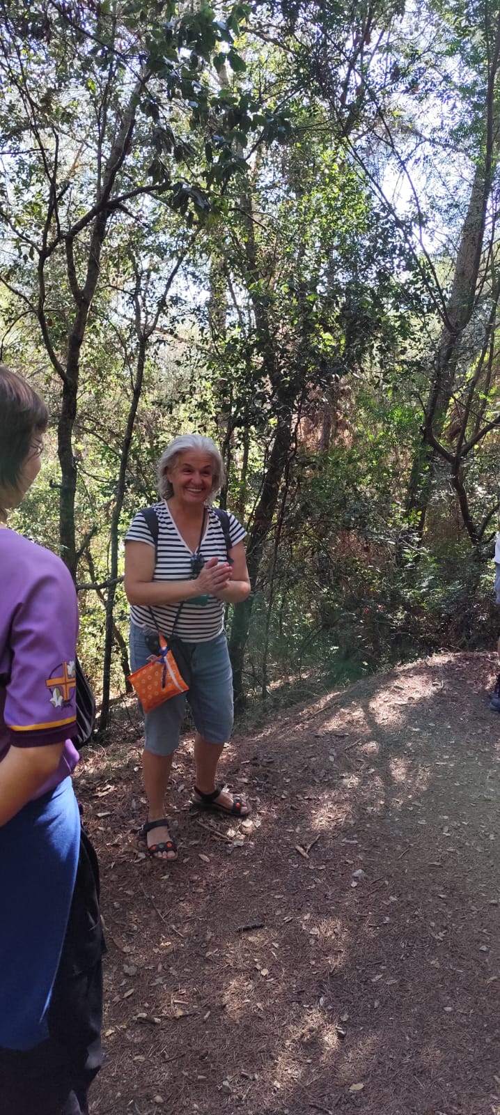Una participante sonríe y habla al grupo en un sendero del bosque durante la paseada de otoño