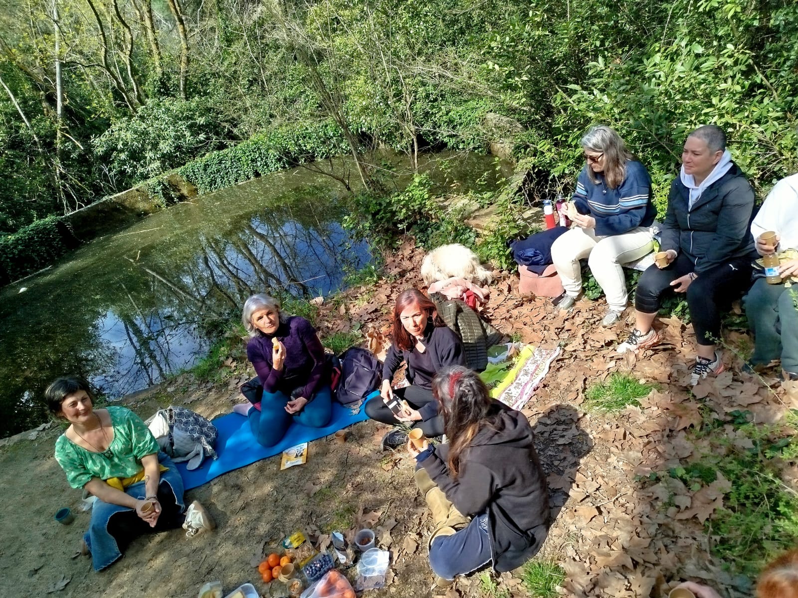 Grupo reunido en una pausa junto al agua durante una paseada aromática de primavera