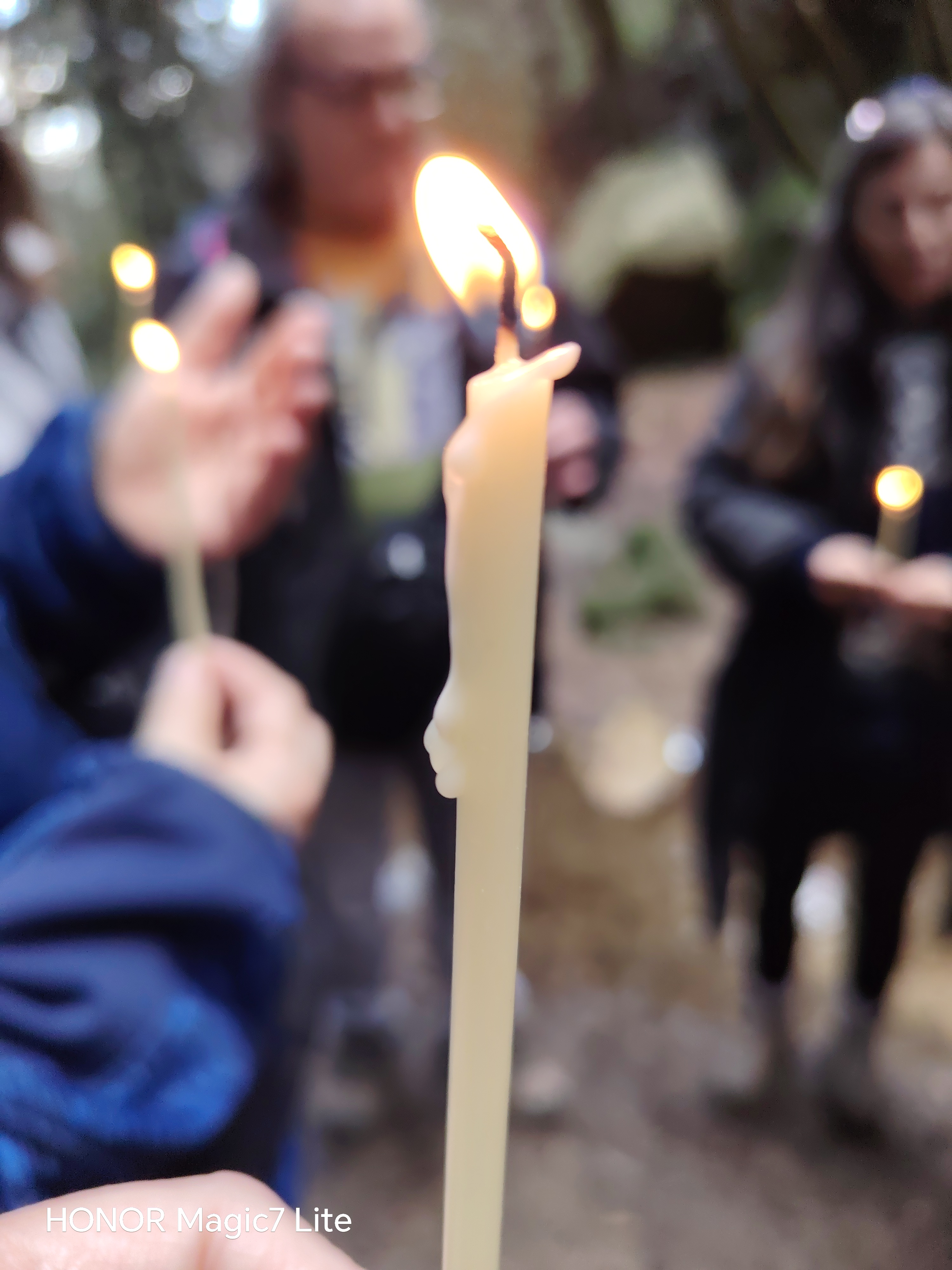Manos sosteniendo velas encendidas en el bosque durante el ritual de invierno de una paseada aromática