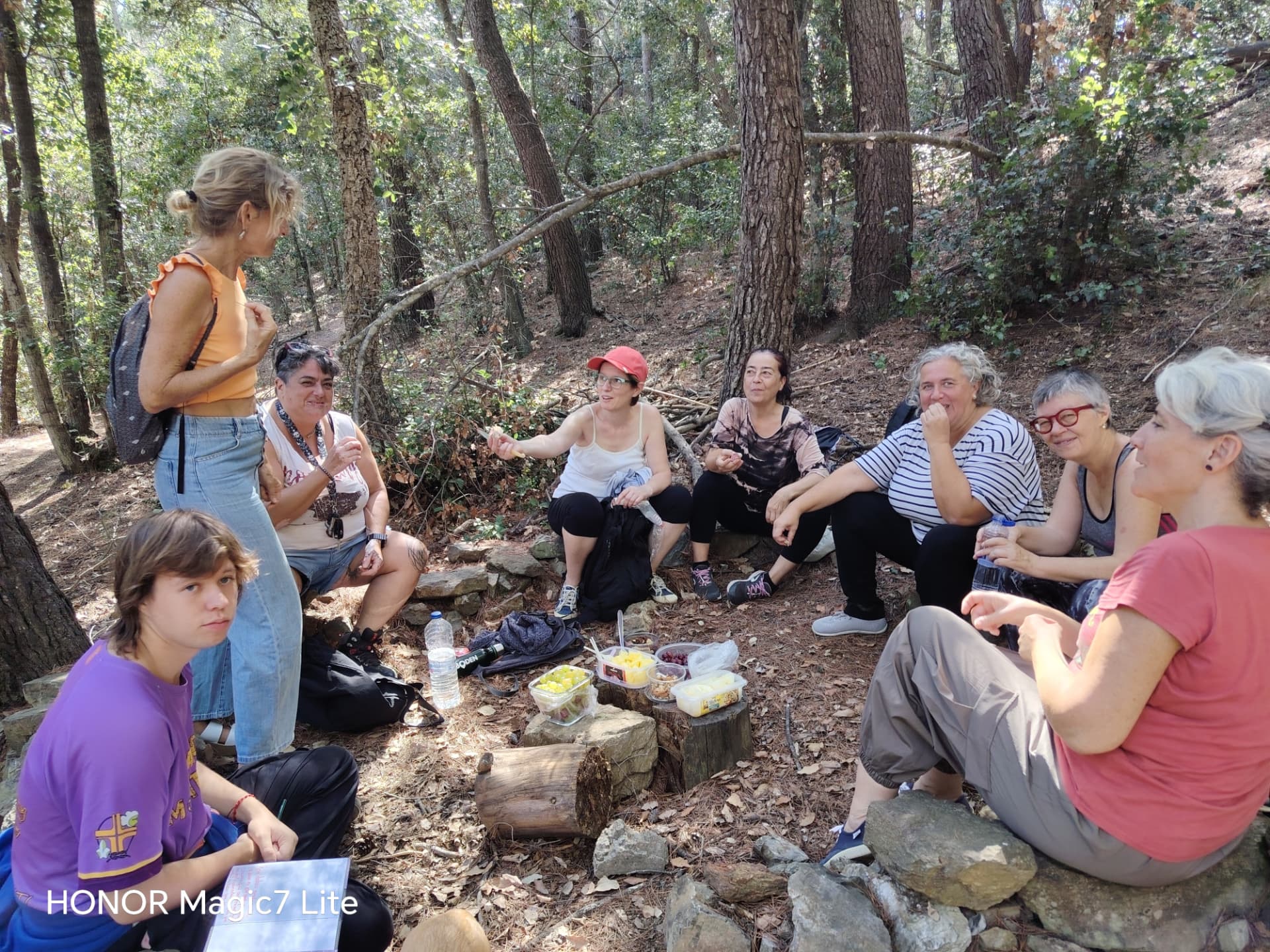 Grupo reunido para compartir comida y conversación en un claro del bosque durante la paseada de otoño